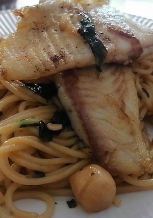 Una foto de Merluza austral con espaguetis y ostiones al ajillo con cebollín y cilantro. 