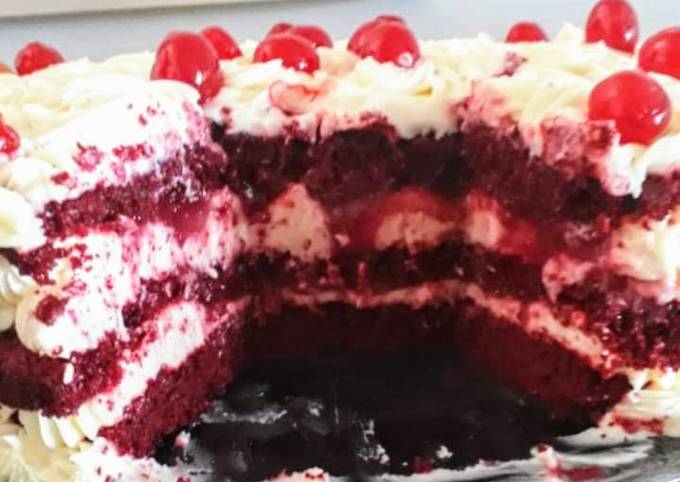 Bolo de veludo vermelho com cereja em um prato branco e uma xícara de café