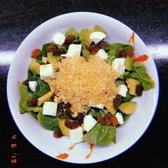 Una foto de Ensalada de espinacas, cous-cous, aguacate, mozzarella y pasas