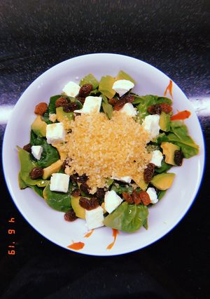 Una foto de Ensalada de espinacas, cous-cous, aguacate, mozzarella y pasas