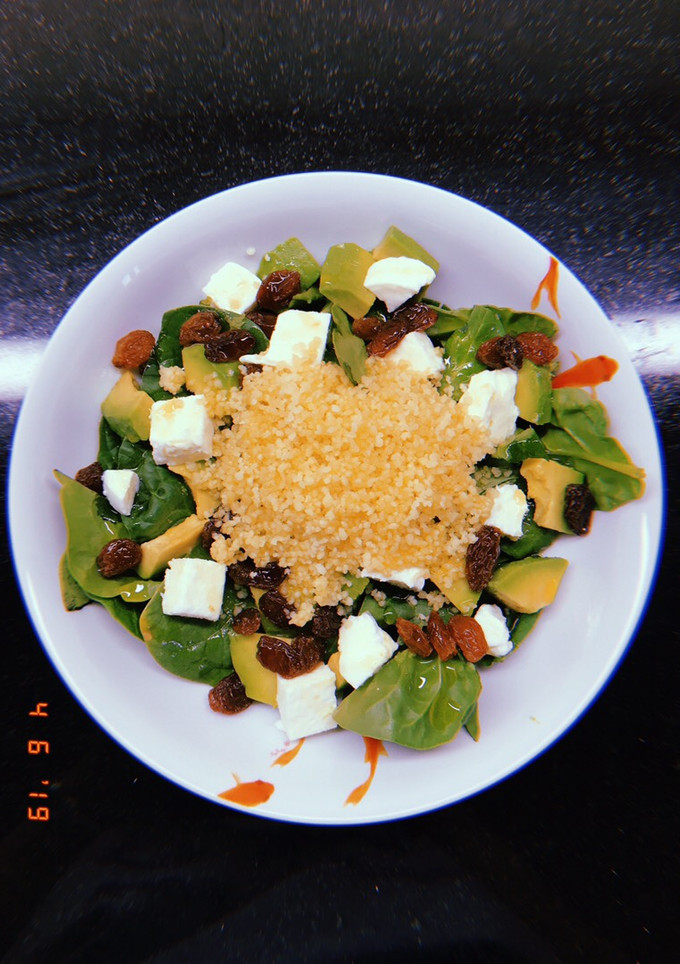 Una foto de Ensalada de espinacas, cous-cous, aguacate, mozzarella y pasas