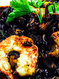 Una foto de Arroz negro integral con chipirones gambas vieyras y mejillones