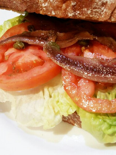 Una foto de Bocata de anchoas con lechuga, tomate y alcaparras