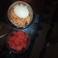 A picture of Jollof Spaghetti and egg with watermelon.