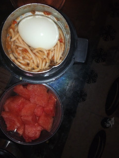 A picture of Jollof Spaghetti and egg with watermelon.