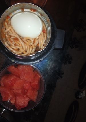 A picture of Jollof Spaghetti and egg with watermelon.