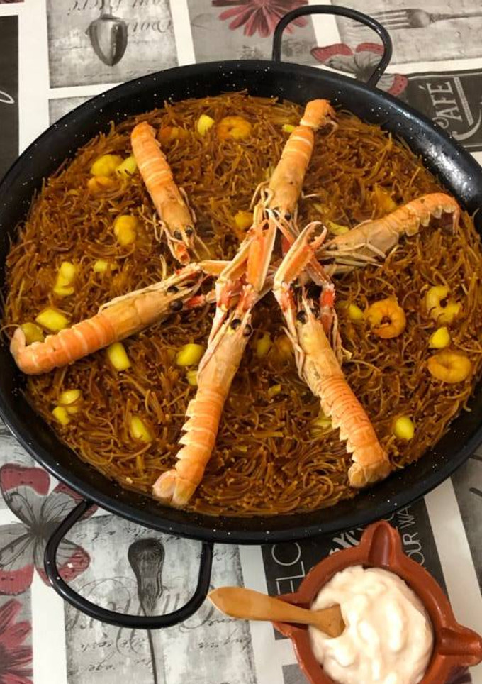 Una foto de Fideuá con sepia gambas y cigalas