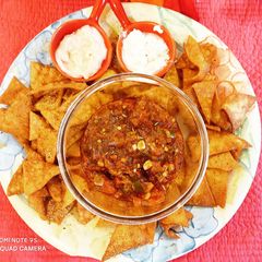 A picture of Nachos with salsa and dips.