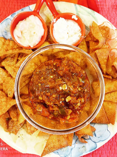 A picture of Nachos with salsa and dips.