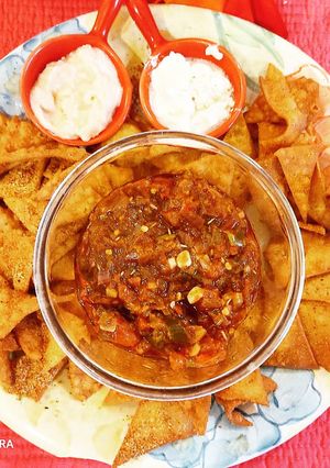 A picture of Nachos with salsa and dips.