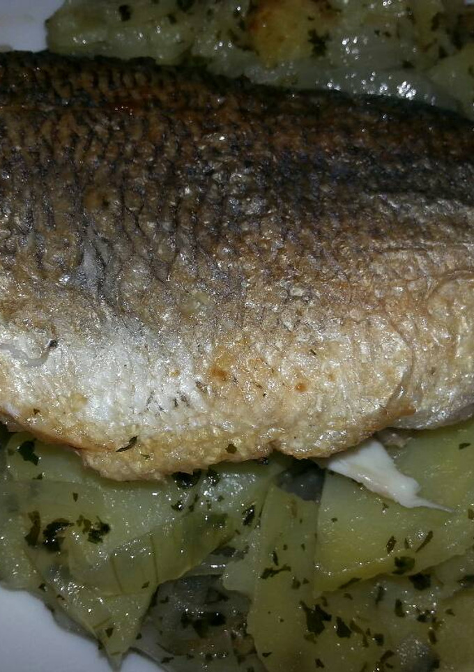 Una foto de Dorada a la sartén en cama de patatas