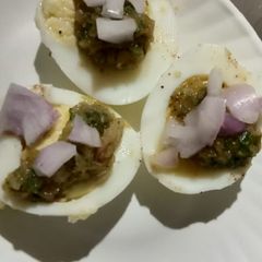 A picture of Boiled eggs with green chutney and onion.
