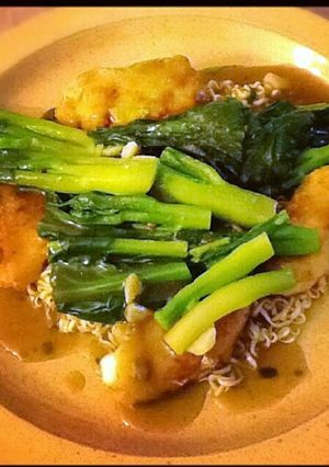 A picture of Egg noodle and red snapper fillet w/ gravy sauce.