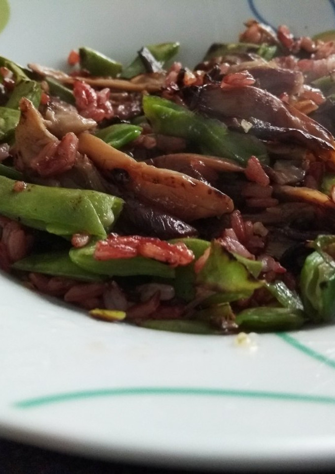 Una foto de Arroz rojo salteado con setas y vainas