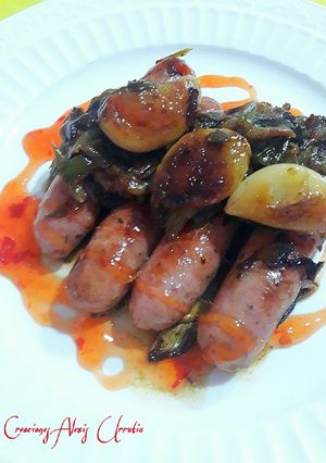 Foto principal de Salchichas de pollo con con cebolletas tiernas y ajos confitados