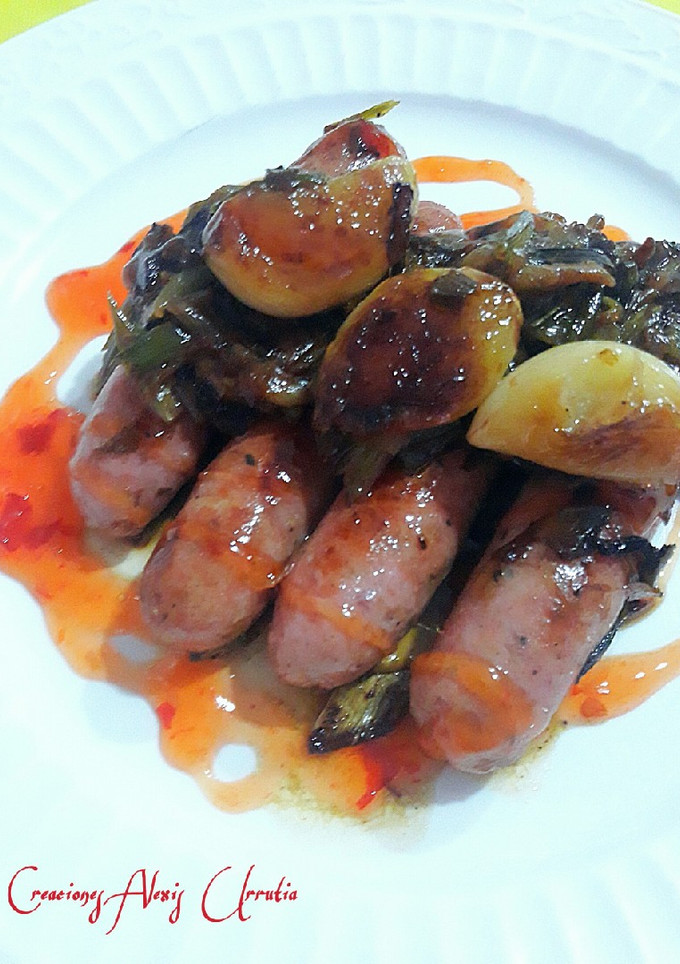 Una foto de Salchichas de pollo con con cebolletas tiernas y ajos confitados
