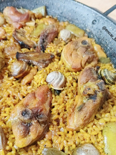 Una foto de Paella valenciana con caracoles y romero