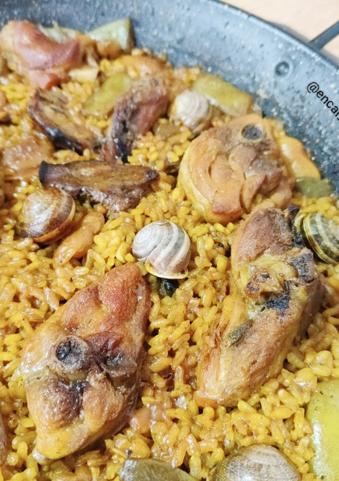 Una foto de Paella valenciana con caracoles y romero