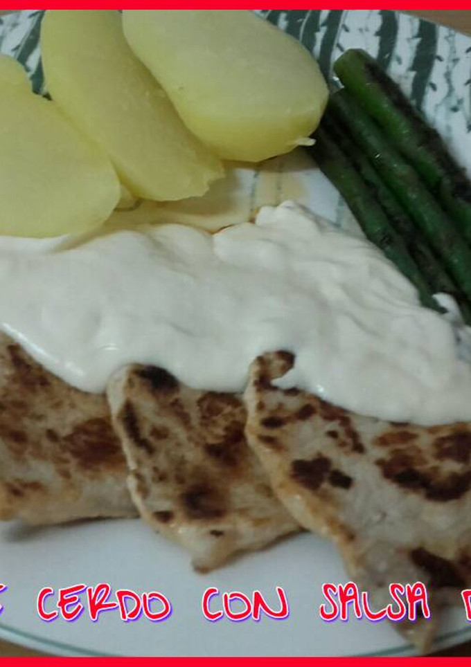 Una foto de Lomo de cerdo con salsa de queso y guarnición