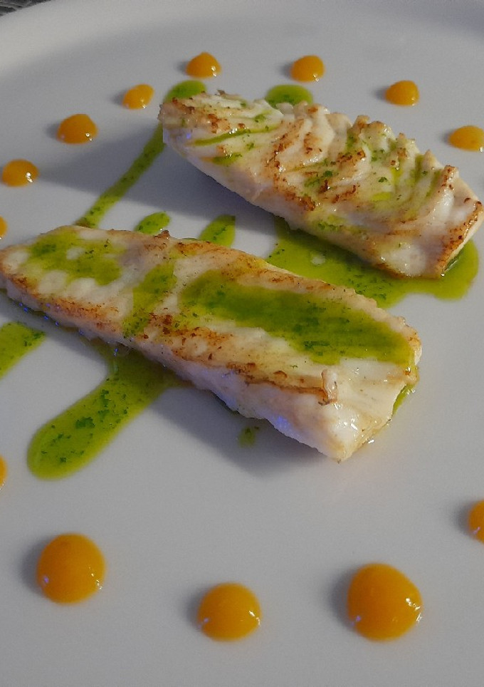 Una foto de Rodaballo con aceite de perejil y cebollino con coolie de mango