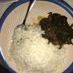 A picture of Rice with ugu soup.