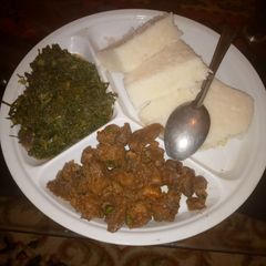 A picture of Ugali served with marinated beef and steamed spinach.