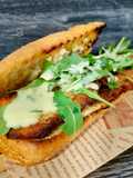 Bocadillo de pollo marinado empanado con rúcula y salsa de parmesano
