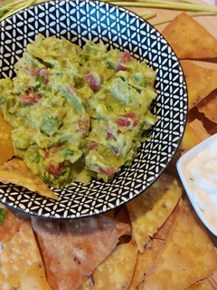 A picture of Guacamole with Nachos and sour cream.