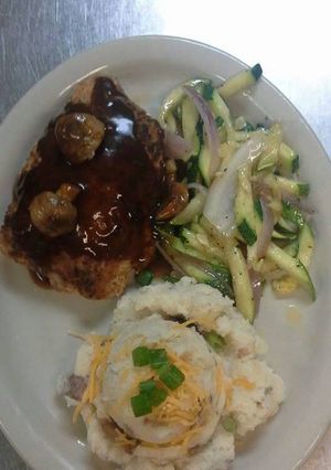 A picture of Stuffed pork chop topped with mushroom bordelaise sauce.
