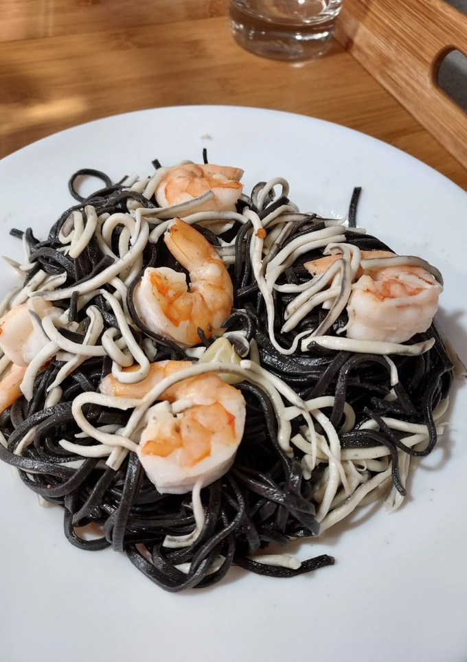 Una foto de Pasta negra con gulas y langostinos