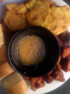 A picture of Carnitas fritas con tostones garlic sauce and long bread....