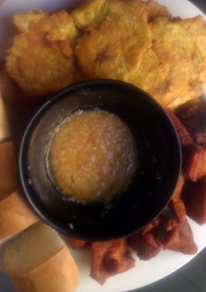 A picture of Carnitas fritas con tostones garlic sauce and long bread....