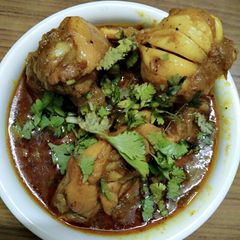 A picture of Chicken curry with whole garlic.
