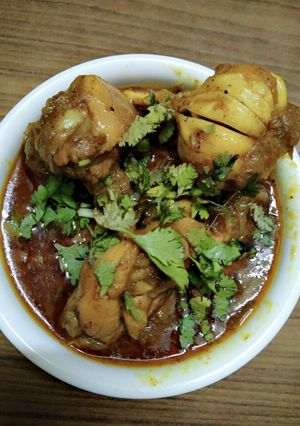A picture of Chicken curry with whole garlic.