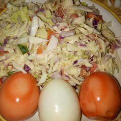 A picture of Cabbage and tomatoes salad with coloured eggs.