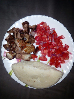 A picture of Oven roasted goat meat with ugali n kachumbari.