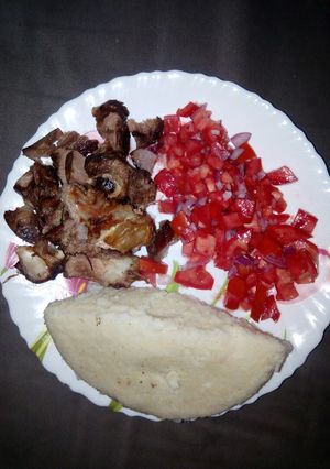 A picture of Oven roasted goat meat with ugali n kachumbari.