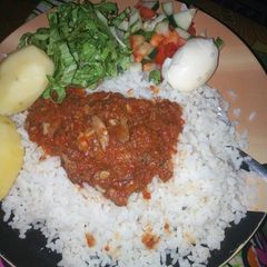 A picture of Rice and stew with boiled potatoes,egg and salad.