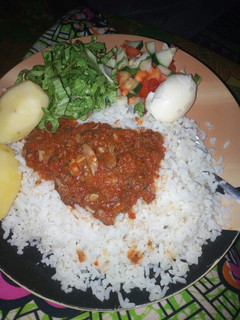 A picture of Rice and stew with boiled potatoes,egg and salad.