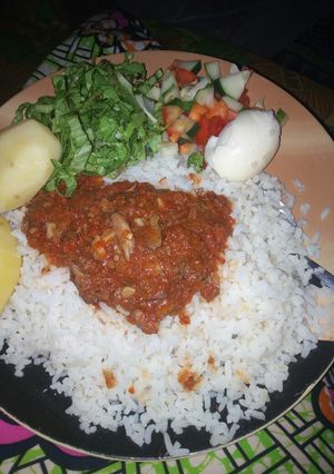 A picture of Rice and stew with boiled potatoes,egg and salad.