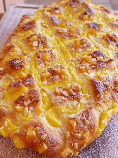 Una foto de Coca de Sant Joan 2024 v2: De crema, naranja confitada, almendras y piñones