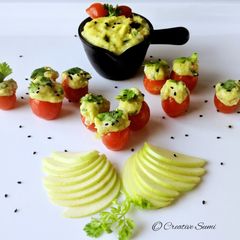 A picture of Cherry tomatoes stuffed with guacamole.
