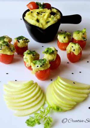 A picture of Cherry tomatoes stuffed with guacamole.