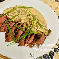 A picture of Ostrich steak with red wine and mushroom sauce.