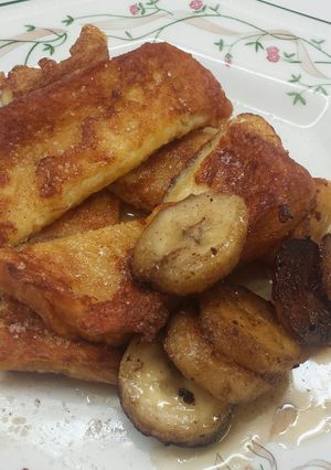 A picture of French Toast with bananas and Maple Syrup.
