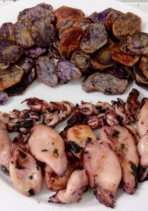 Una foto de Chipirones al ajillo y patatas violetas fritas