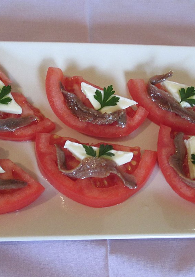 Una foto de Anchoas y queso brie sobre tomates ensaladera