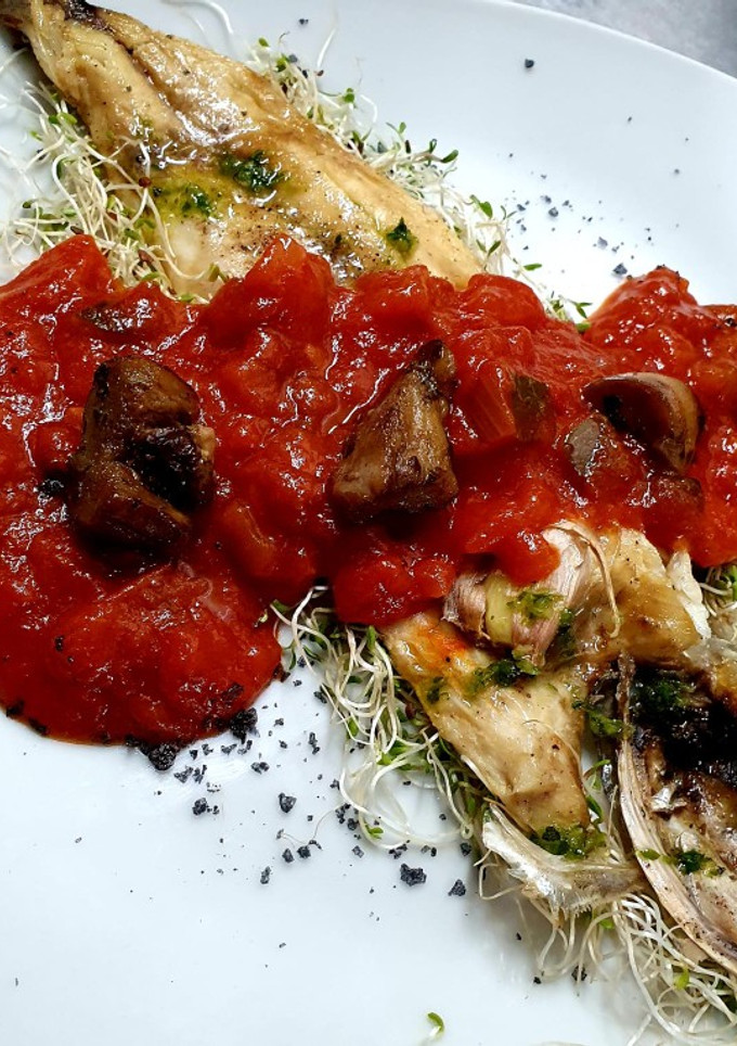 Una foto de Lubina a la plancha con pisto manchego y coronada con boletus