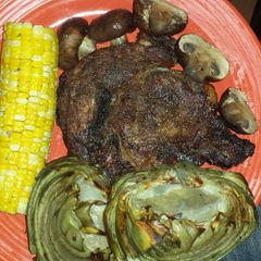 A picture of Ribeye steak w/corn, bbq mushrooms, bbq artichokes.