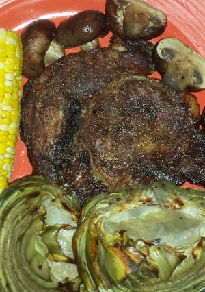 A picture of Ribeye steak w/corn, bbq mushrooms, bbq artichokes.